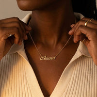 Thumbnail for Minimalist Name Necklace in gold with the name Amara, held at the neckline with both hands | SKU: minimalistnn-gold