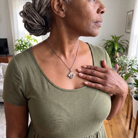 Thumbnail for Woman in an olive dress with her hand on her heart, wearing the silver secret clover photo necklace | SKU: TPH-CLVN-SILVER