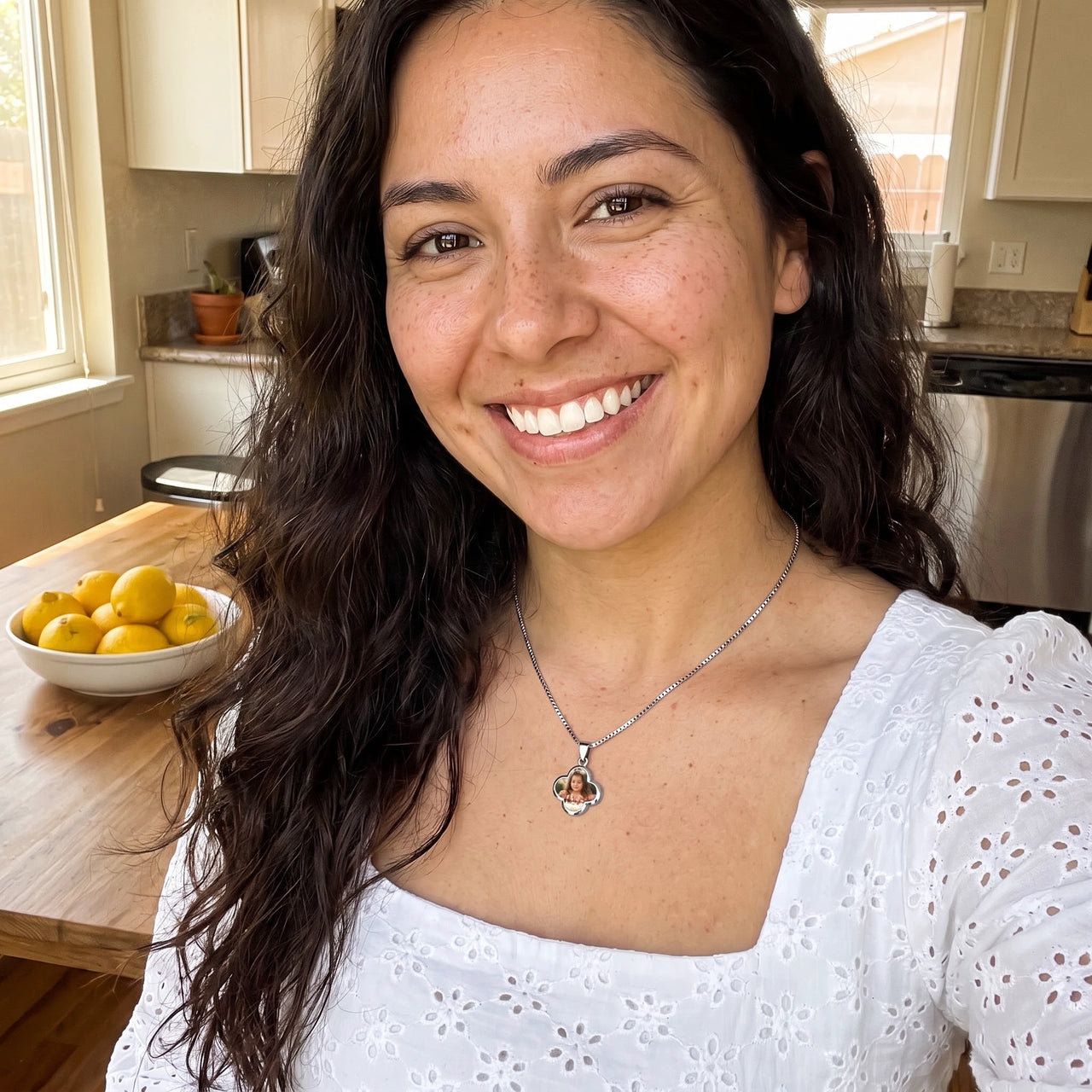 Smiling woman with long dark hair in a white eyelet top in her kitchen, wearing the silver secret clover photo necklace | SKU: TPH-CLVN-SILVER