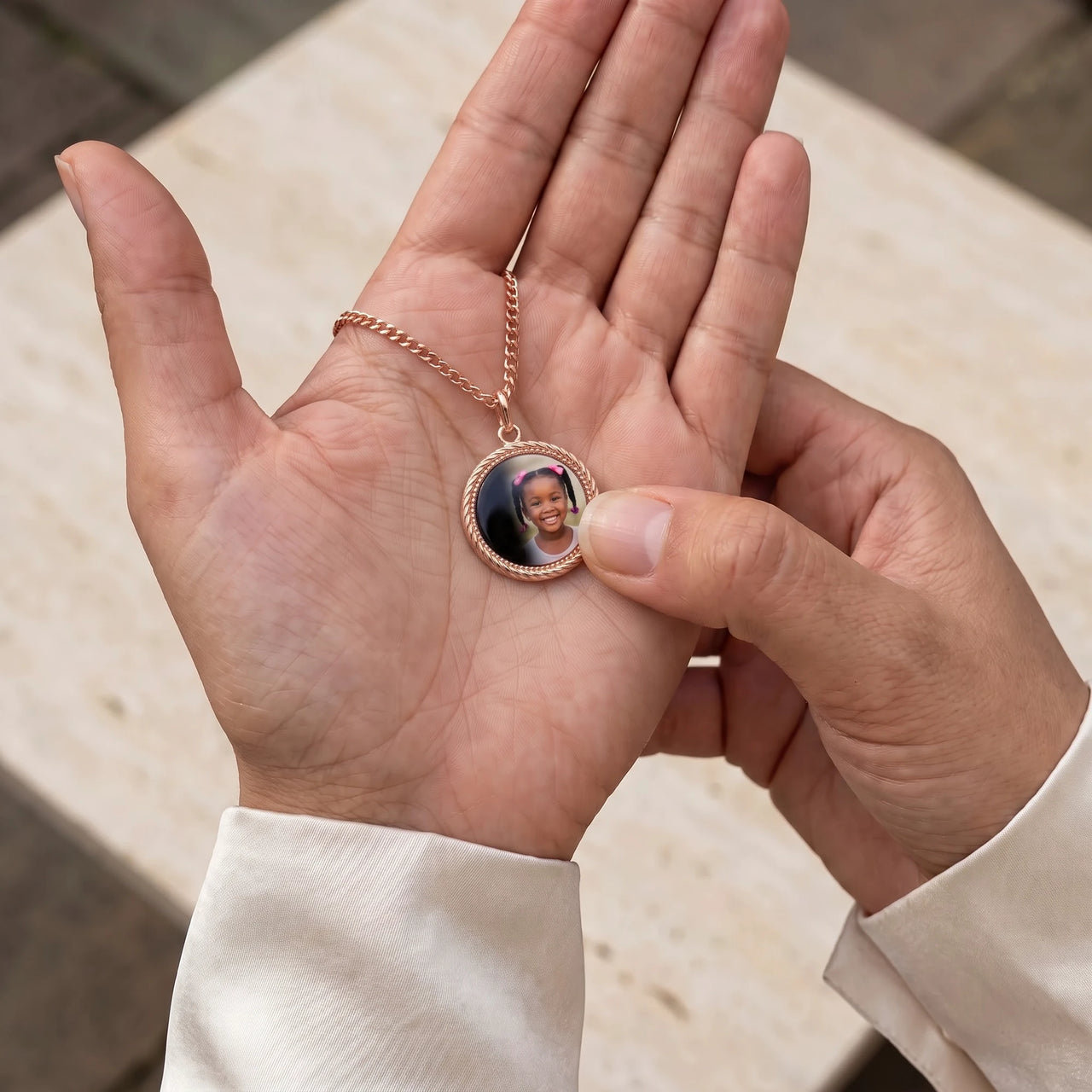 Thumb warming the rose gold round pendant: the hidden photo appears under the thumb while the rest stays black | SKU: TPH-RNDN-ROSEGOLD